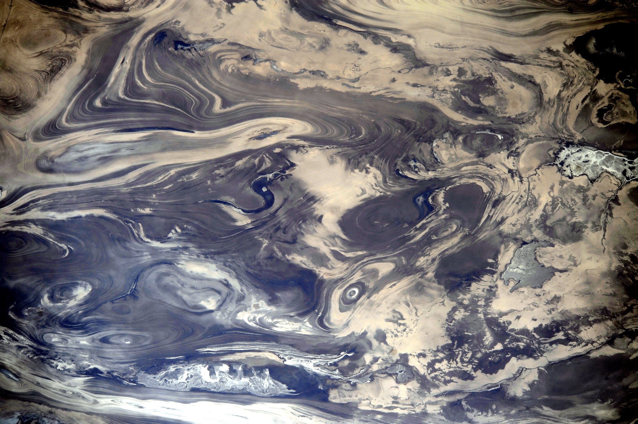 Orbital view of salt, sediment and water patterns in Iran’s Kavir Desert.